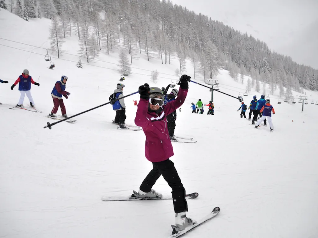 Skifahrerin hält die Stöcke über den Kopf.